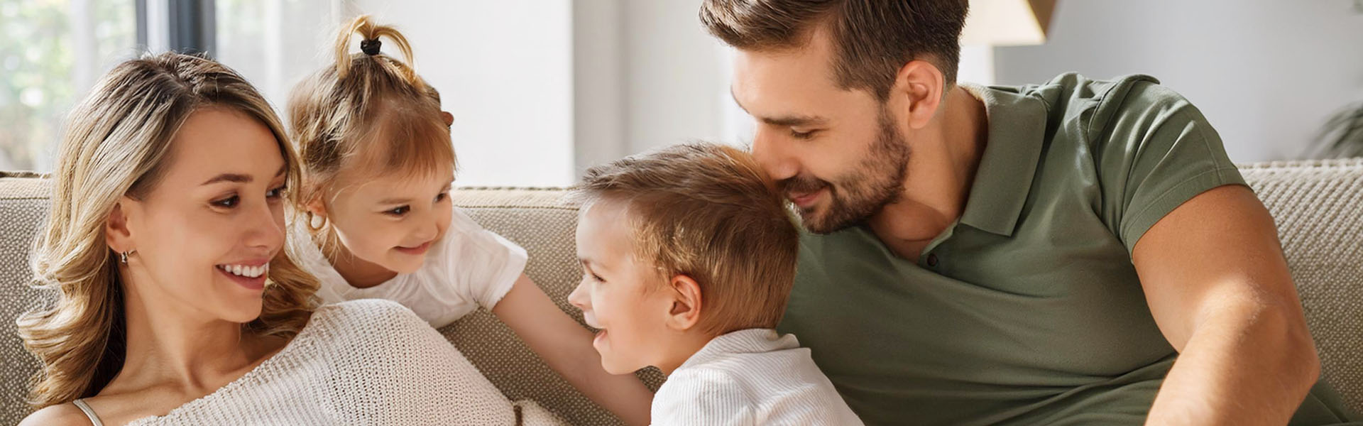 Eine fröhliche vierköpfige Familie kuschelt gemütlich zusammen auf dem Sofa.